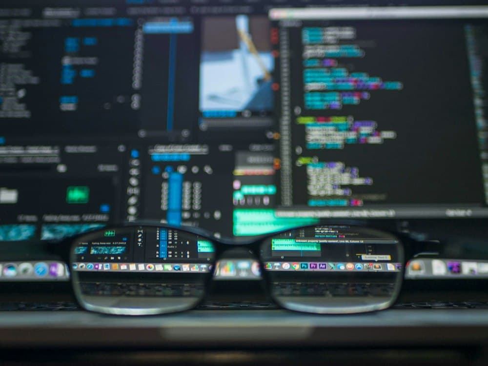 Glasses resting in front of a screen full of code