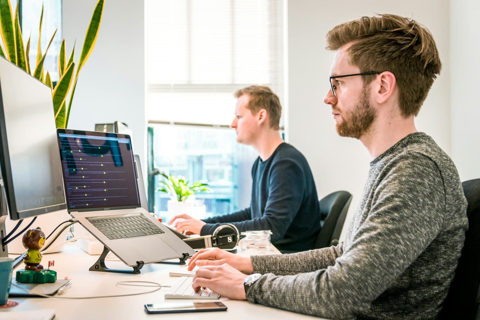 Two engineers working side by side at a bright, modern desk
